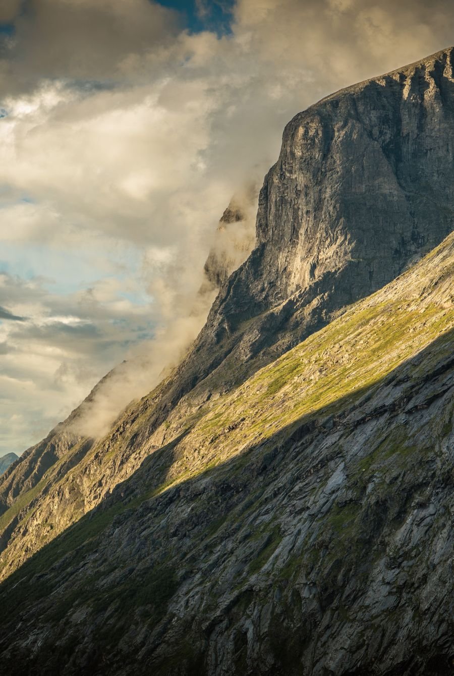 Solen treffer fjellside med himmel og skyer i bakgrunnen